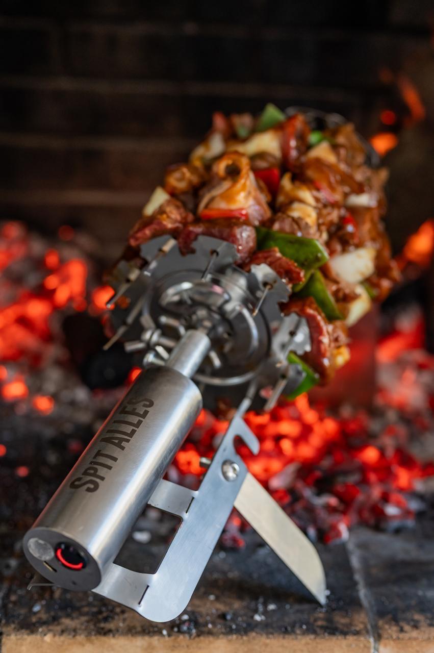 Metal skewer with food over a fire, featuring 'Spit Alles' branding.